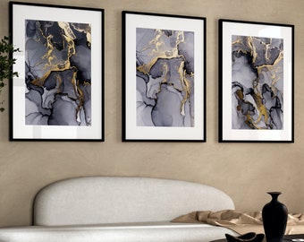 May include: Three framed abstract art prints with a gray and gold marble design. The prints are in black frames and are hanging on a beige wall.