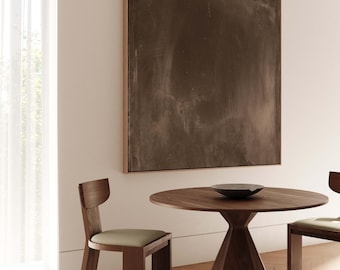 May include: A round wooden table with a conical base and two wooden chairs with upholstered seats. A framed abstract painting hangs on the wall behind the table.