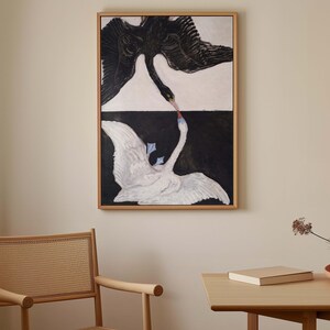 May include: A framed painting of two swans, one black and one white, with their necks intertwined. The swans are depicted against a black and white background, creating a striking contrast.