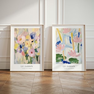May include: Two framed floral art prints. The left print features a bouquet of pink, yellow, and blue flowers. The right print has pink and blue abstract floral shapes. Both prints have the text "LE JARDIN" and "Les fleurs de la campagne".