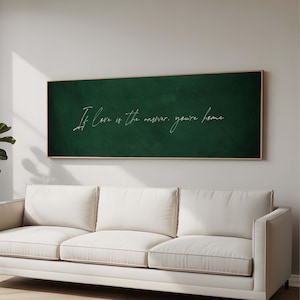 Könnte beinhalten: Ein rechteckiger, gerahmter Tafellook mit dem Zitat "If love is the answer, you're home" in weißer Schrift. Die Tafel ist grün und hängt über einem weißen Sofa in einem hellen Raum.
