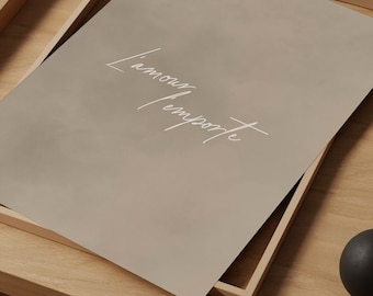 May include: A framed print with a light brown background and the text "L'amour l'emporte" in white cursive writing.