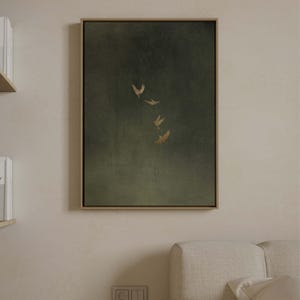May include: A framed canvas art print with a dark green, textured background. Four gold-coloured bird silhouettes are shown in flight, evoking a sense of movement and calm. The artwork is enclosed in a light brown wooden frame.