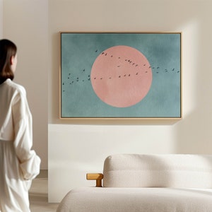Pode incluir: Uma pintura abstrata enquadrada com um grande círculo rosa no centro e um bando de pássaros pretos voando sobre um fundo azul-turquesa.