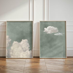 Könnte beinhalten: Zwei gerahmte Drucke von abstrakten Wolken vor einem matten grünen Hintergrund. Die Drucke sind in einfachen, hellen Holzrahmen.