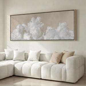 Puede incluir: Una pieza de arte mural rectangular horizontal de gran tamaño que presenta una pintura detallada de nubes blancas esponjosas sobre un fondo beige suave y apagado. La obra está enmarcada en un marco de madera fina de tono claro.