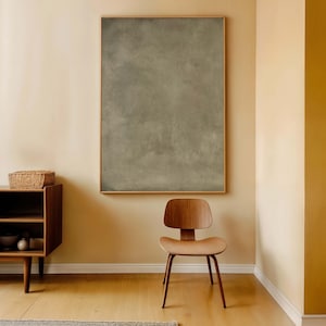 May include: A room with a large framed abstract painting in shades of gray and brown. A wooden chair with a curved back and a low wooden cabinet with a woven basket on top are in the foreground. The walls are painted in a warm, neutral tone.