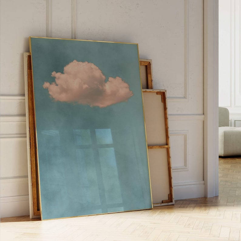 May include: A framed print of a single, large, pink cloud against a blue sky. The frame is gold and the print is on a textured canvas.