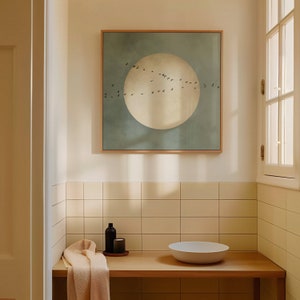 K&ouml;nnte beinhalten: Ein Badezimmer mit einer wei&szlig;en gekachelten Wand, einer Holztheke und einem gerahmten Druck eines gro&szlig;en wei&szlig;en Kreises mit V&ouml;geln, die um ihn herum fliegen. Auf der Theke stehen eine kleine Flasche und eine Kerze sowie eine wei&szlig;e Sch&uuml;ssel.
