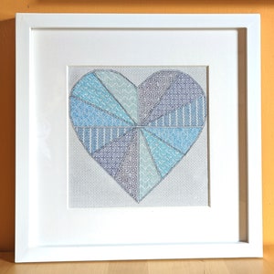 May include: A white framed picture with a blue and purple heart-shaped design made of different geometric patterns.