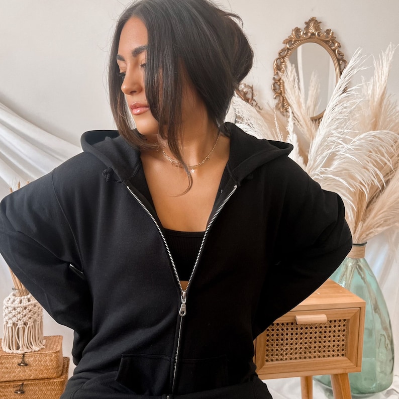 May include: A black zip-up hoodie with a hood. The hoodie is made of a soft, comfortable fabric and has a relaxed fit.