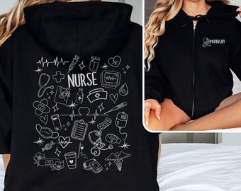 May include: Black zip-up hoodie with white medical-themed illustrations and the word "NURSE" on the back. The front features the name "AMANDA.RM" and a stethoscope design. The hoodie is made of a soft material.