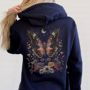 May include: Navy blue hoodie with a large butterfly graphic on the back. The butterfly is surrounded by flowers and has a crescent moon above it.