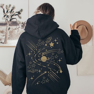 May include: Black hooded sweatshirt with a gold graphic of planets, stars, and shooting stars on the back.