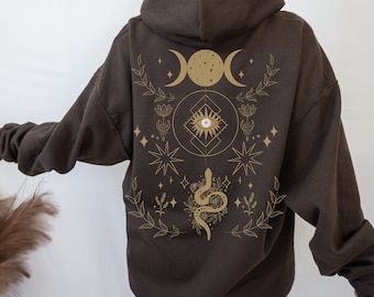 May include: A brown hoodie with a gold graphic print of a snake, moon phases, stars, and an eye. The graphic is centered on the back of the hoodie.