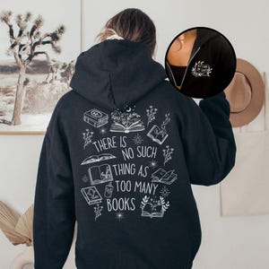 May include: Black hooded sweatshirt featuring white illustrations of books and floral designs, with the text "THERE IS NO SUCH THING AS TOO MANY BOOKS" on the back. A small logo is on the chest.