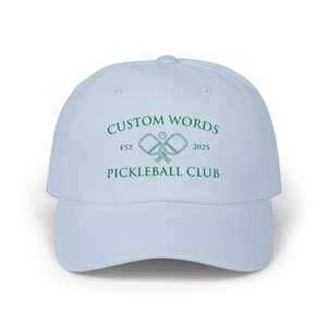 Custom pickleball hat embroidered with your team of clubs name. Features pickle ball paddles and the year.