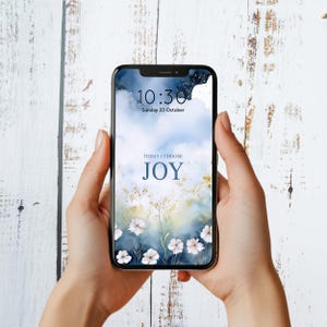 May include: A smartphone displaying a blue and white watercolor background with white flowers and the text "TODAY I CHOOSE JOY". The time is 10:30 and the date is Sunday 23 October.