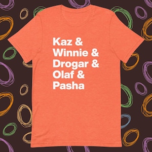 May include: Orange t-shirt with white text that reads "Kaz & Winnie & Drogar & Olaf & Pasha"