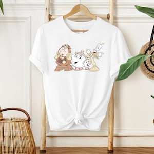 May include: White t-shirt with a graphic print of characters from the Disney movie Beauty and the Beast. The characters are Cogsworth, Mrs. Potts, and Lumiere.