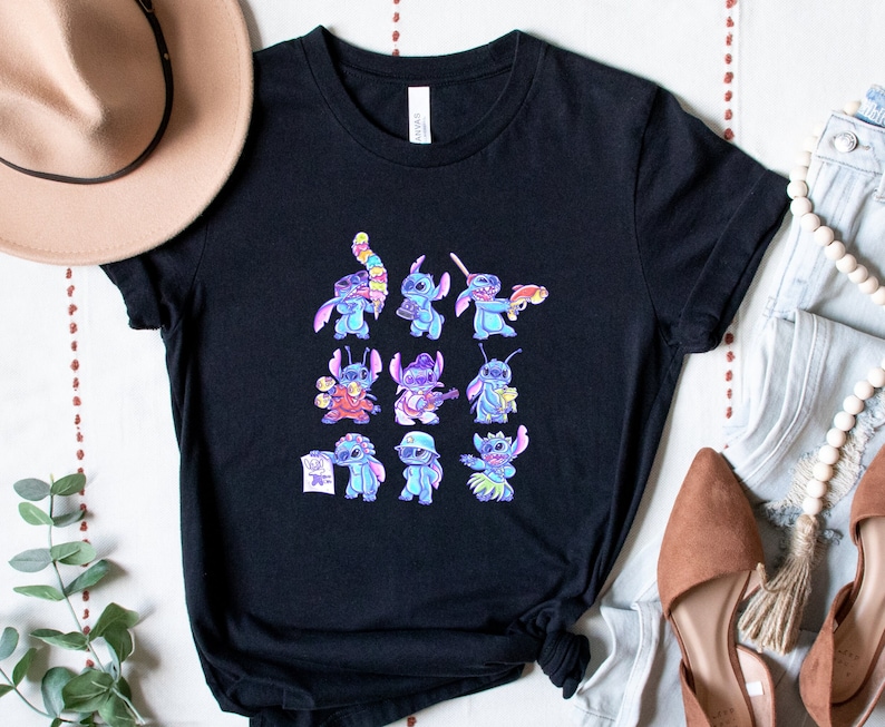 K&ouml;nnte beinhalten: Schwarzes T-Shirt mit einer farbenfrohen Grafik der Figur Stitch in verschiedenen Posen. Die Grafik zeigt Stitch mit einem Blaster, der Gitarre spielt und einen Hut tr&auml;gt. Das Shirt besteht aus einem weichen Material.