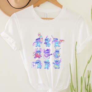 K&ouml;nnte beinhalten: Wei&szlig;es T-Shirt mit einem farbenfrohen Aufdruck der Figur Stitch in verschiedenen Posen. Der Aufdruck zeigt Stitch mit einer Kamera, Gitarre spielend und mit einem Hula-Rock. Das T-Shirt besteht aus einem weichen, leichten Material.