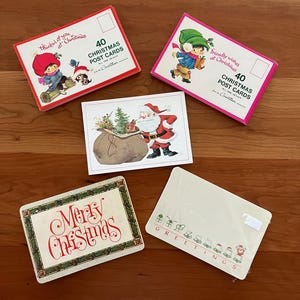 May include: A collection of vintage Christmas postcards. The postcards feature festive illustrations of Santa Claus, children, and holiday greetings. The text on the postcards includes phrases like "Merry Christmas" and "Greetings". The postcards are packaged in sets of 40.