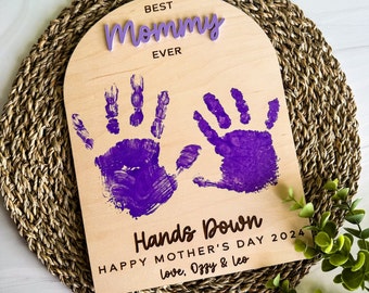 May include: Wooden sign with purple handprints and the text "Best Mommy Ever" and "Hands Down Happy Mother's Day 2024 Love, Ozzy & Leo"