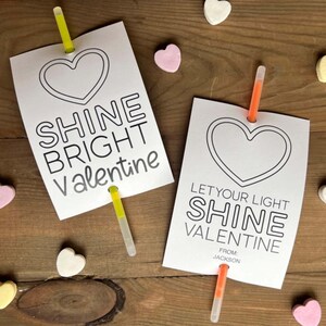 May include: Two printable Valentine's Day cards with glow sticks attached. The cards feature a heart shape and the text "Shine Bright Valentine" and "Let Your Light Shine Valentine".