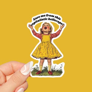 May include: A sticker featuring a vintage illustration of a young girl with her arms raised, wearing a yellow dress with red accents, and red shoes. The text "Save me from this capitalistic hellscape!" is written in a bold, black font around the girl.
