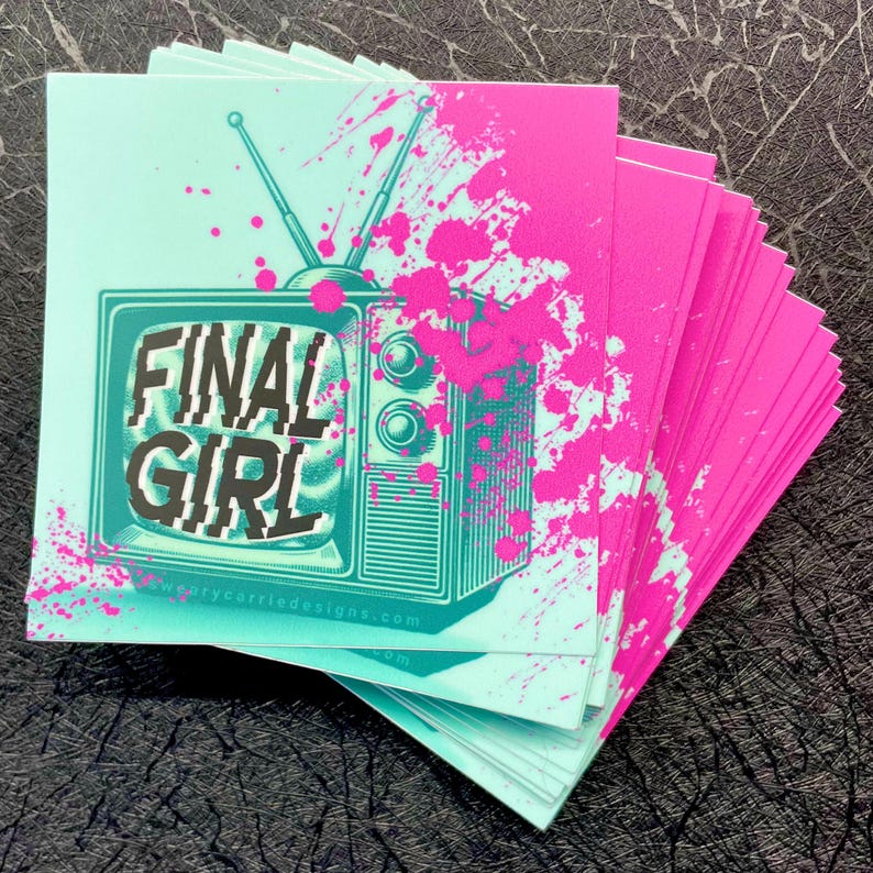 K&ouml;nnte beinhalten: Ein Stapel Aufkleber mit einem Retro-Fernseher mit dem Text "FINAL GIRL" in schwarzen Buchstaben auf einem blaugr&uuml;nen Hintergrund. Der Fernseher ist von rosa Farbflecken auf einem blaugr&uuml;nen Hintergrund umgeben.