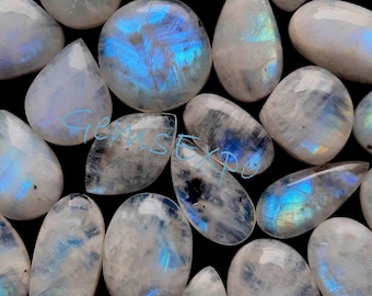 May include: A collection of iridescent moonstone cabochons in various shapes and sizes. The stones have a milky white base with a blue sheen.