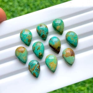 May include: A collection of ten teardrop-shaped turquoise gemstones. The stones display a mix of vibrant teal and brown hues, with natural veining patterns. They are arranged on a white surface, showcasing their polished appearance.