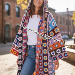 May include: A colorful, hooded crochet coat with a patchwork design. The coat features a variety of colors, including blue, orange, purple, and white. The text "Handmadebybircool" is visible on the coat. The person is wearing blue jeans and a white shirt.