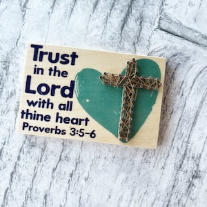 May include: Wooden sign with a teal heart and a cross made of string wrapped around nails. The sign reads "Trust in the Lord with all thine heart Proverbs 3:5-6".