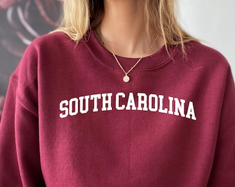 May include: Maroon sweatshirt with the text "SOUTH CAROLINA" in white lettering.