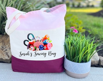 May include: A pink, white, and burgundy tote bag with a design of sewing supplies and the text "Sarah's Sewing Bag".