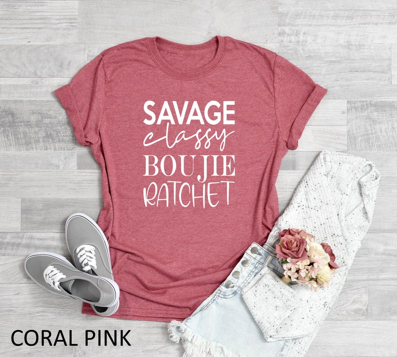 May include: Coral pink t-shirt with the text "SAVAGE classy BOUJIE RATCHET" in white lettering.