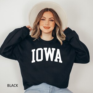 May include: Black sweatshirt with white text that reads "IOWA" in a collegiate font.
