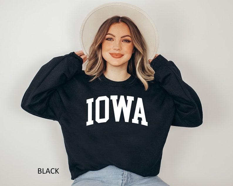 May include: Black sweatshirt with white text that reads "IOWA" in a collegiate font.