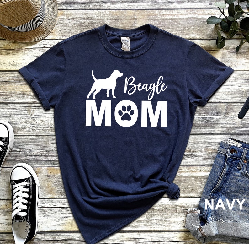 Op de afbeelding: Donkerblauw T-shirt met een wit silhouet van een beagle-hond en de tekst "Beagle MOM" met een pootprint.