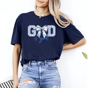 K&ouml;nnte beinhalten: Ein marineblaues T-Shirt mit einem wei&szlig;en und blauen Schleifen-Motiv und dem Text "GOD is good".