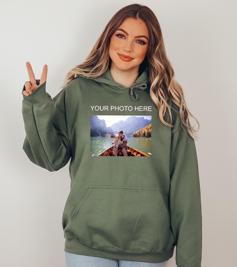 May include: A green hooded sweatshirt with a pocket on the front. The sweatshirt has a photo of a couple in a boat on a lake with mountains in the background. The text "YOUR PHOTO HERE" is printed above the photo.