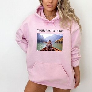 May include: Pink hoodie with a pocket and a photo of a couple on a boat printed on the front. The text "YOUR PHOTO HERE" is printed above the photo.