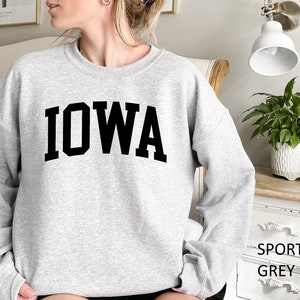 May include: A gray sweatshirt with the word "IOWA" printed in black block letters.