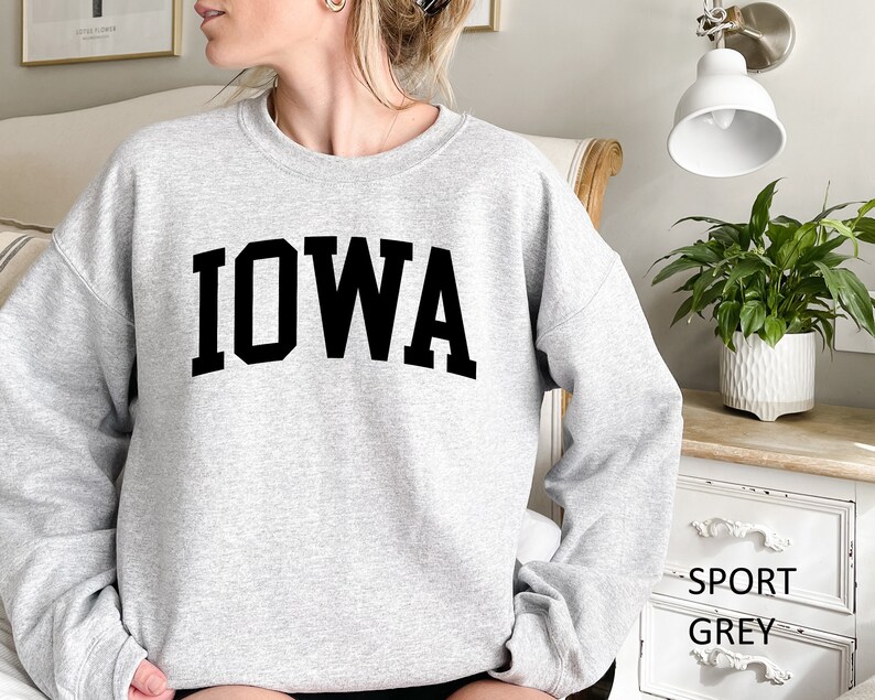 May include: A gray sweatshirt with the word "IOWA" printed in black block letters.
