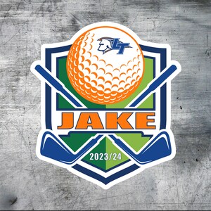 Puede incluir: Una pegatina de golf blanca, azul y verde con una bola de golf, palos de golf cruzados y el texto "JAKE" en naranja. La pegatina tambi&eacute;n incluye el texto "2023/24" en blanco.
