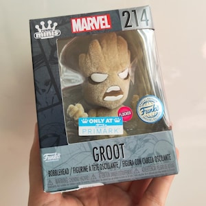 May include: A Funko Minis Marvel Groot bobblehead figure in a clear plastic box. The figure is flocked and has a detailed, textured appearance. The box features the Marvel logo and the Primark logo.