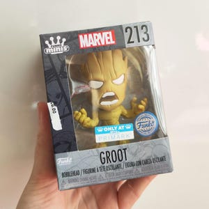 May include: A Funko Mini bobblehead figure of Groot from Marvel, in a clear display case. The box features the Marvel logo and the number 213. The figure is a special edition, only available at Primark. The word 'Groot' is printed on the box.