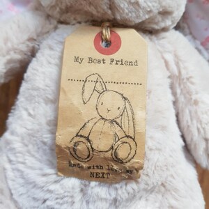 May include: A soft, beige bunny toy with a tag that says "My Best Friend." The tag has a bunny sketch and the text "Made with love by NEXT." The bunny has pink detailing on its ears.